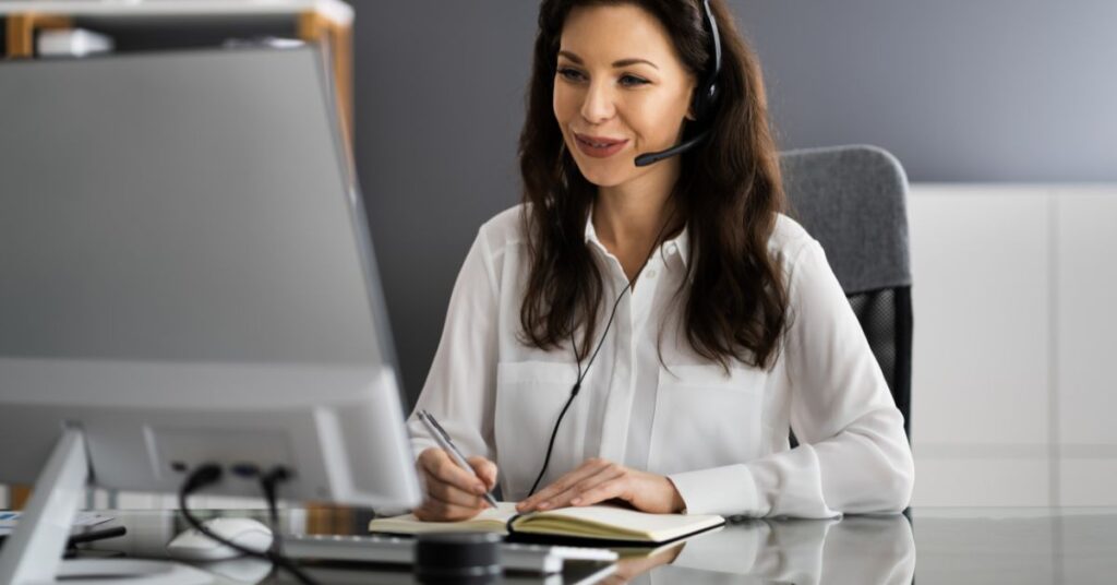A virtual assistant sitting on a desk with laptop.